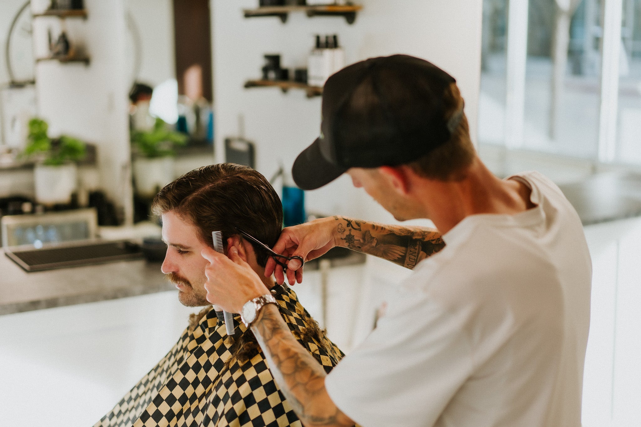 Barber cutting client’s hair with scissors and comb at The Bureau Barbershop in downtown Salt Lake City.
